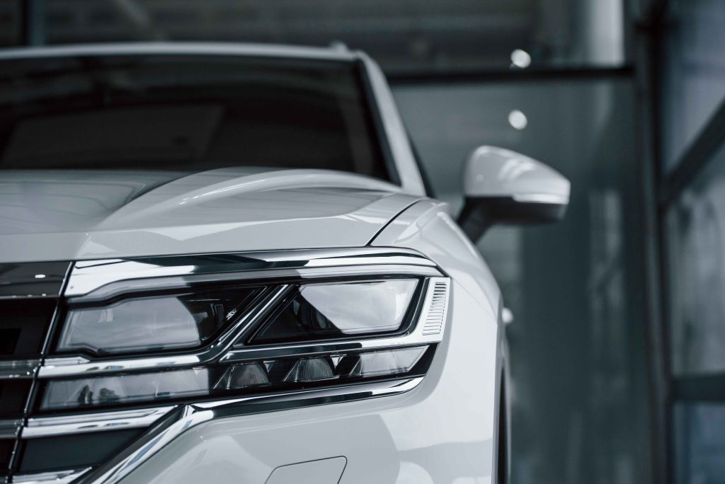 Передня частина білого автомобіля з сучасною LED-оптикою та бічним дзеркалом у салоні авто