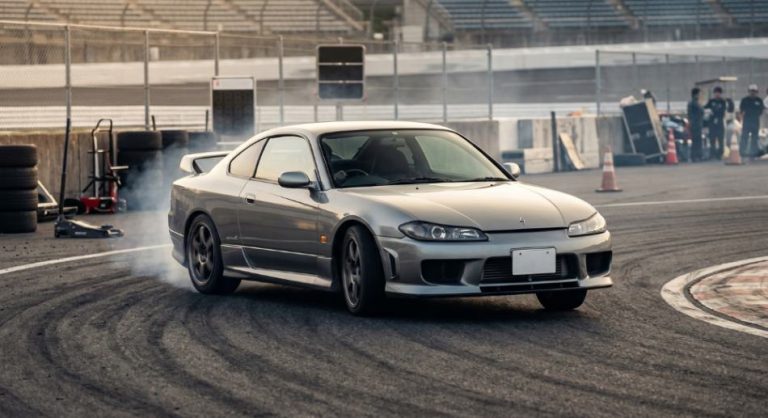Сріблястий спорткар Nissan Silvia S15 дрифтує на гоночній трасі